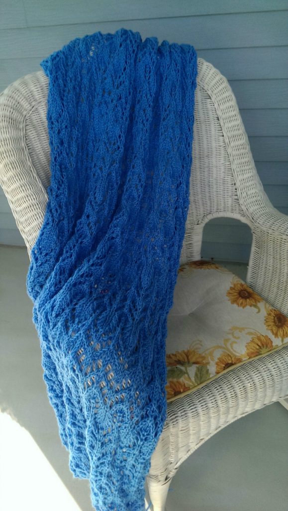 deep blue knit lace afghan on a white wicker chair