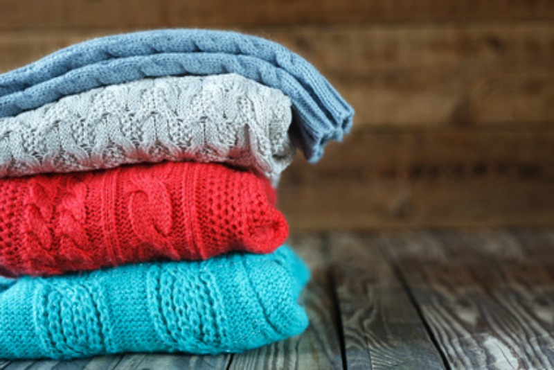 A stack of colorful knitted sweaters for candles in the windows.