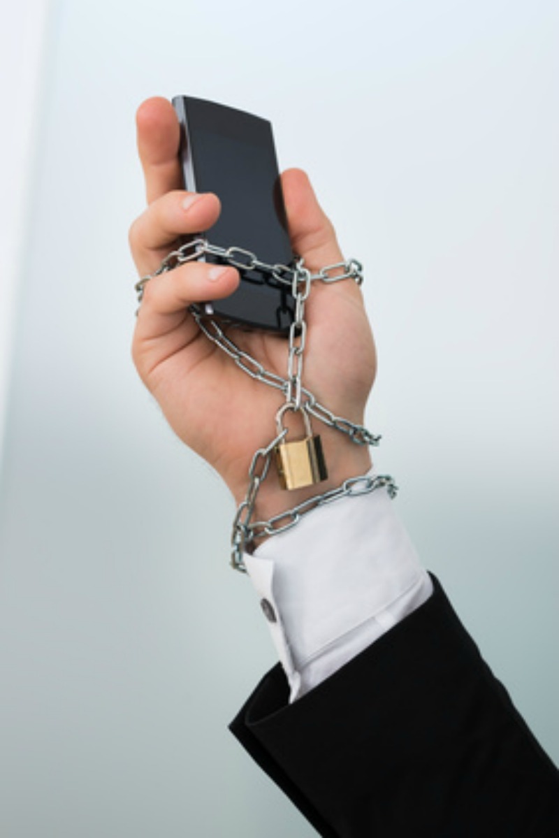 A cellphone chained to a man's hand while he decides to do something or do nothing