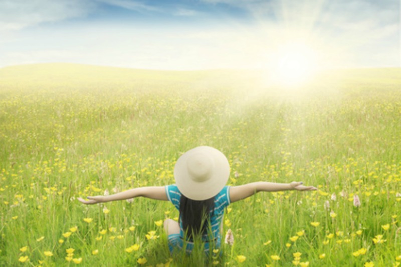 A woman breathing easy in a sun-lit field