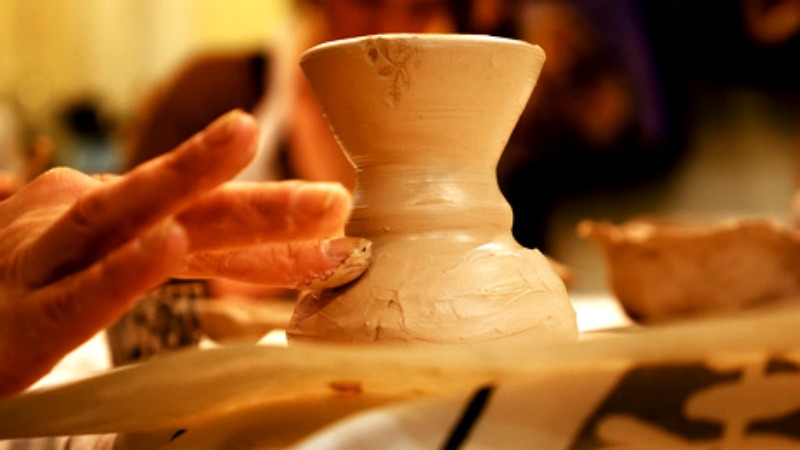 Someone using a spinner to create a clay pot